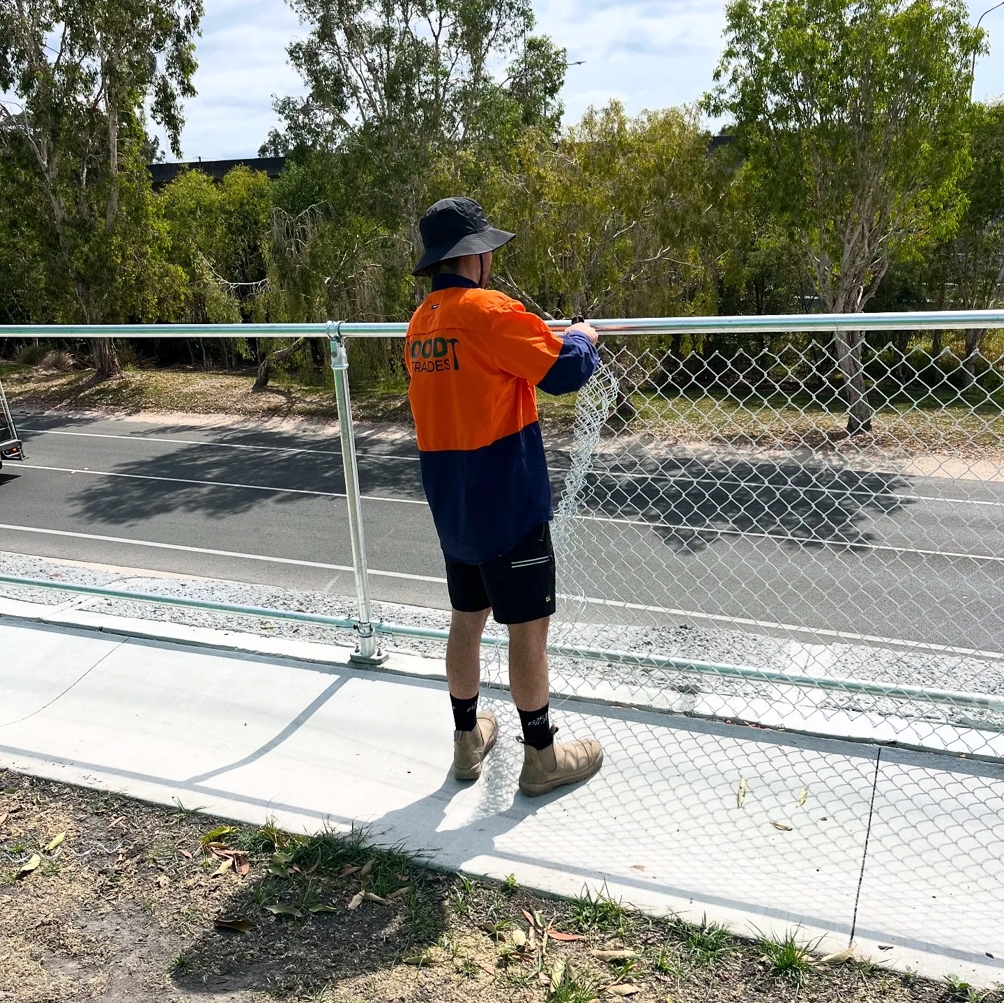 Wood Trades crew installing new chainmesh onto an existing fence framework